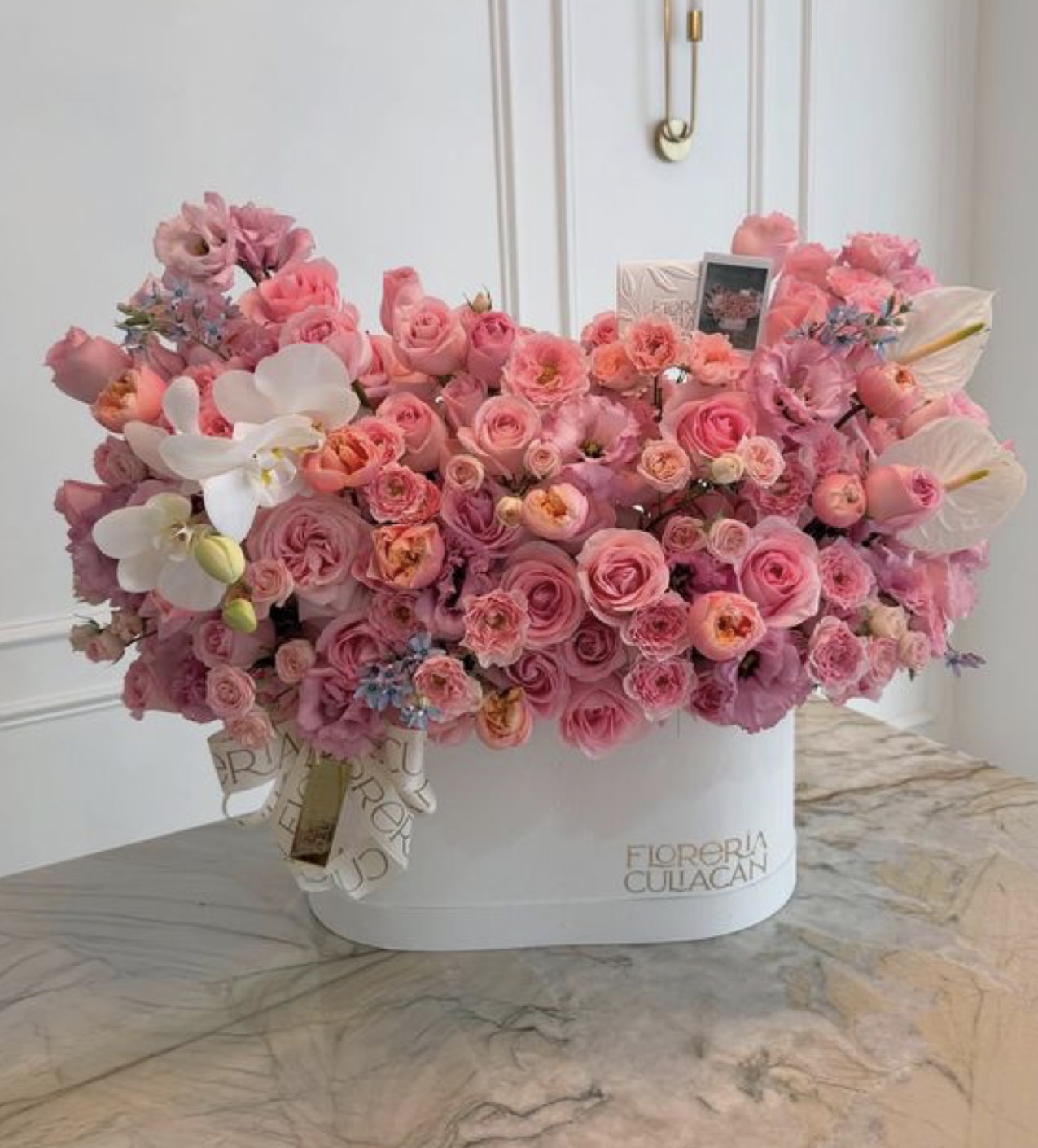 Lush pink garden roses and orchids in a white Pretty hat box